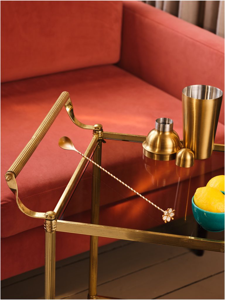 St-Germain bar tools and lemons styled on drinks trolley and red sofa, colour-led product photography