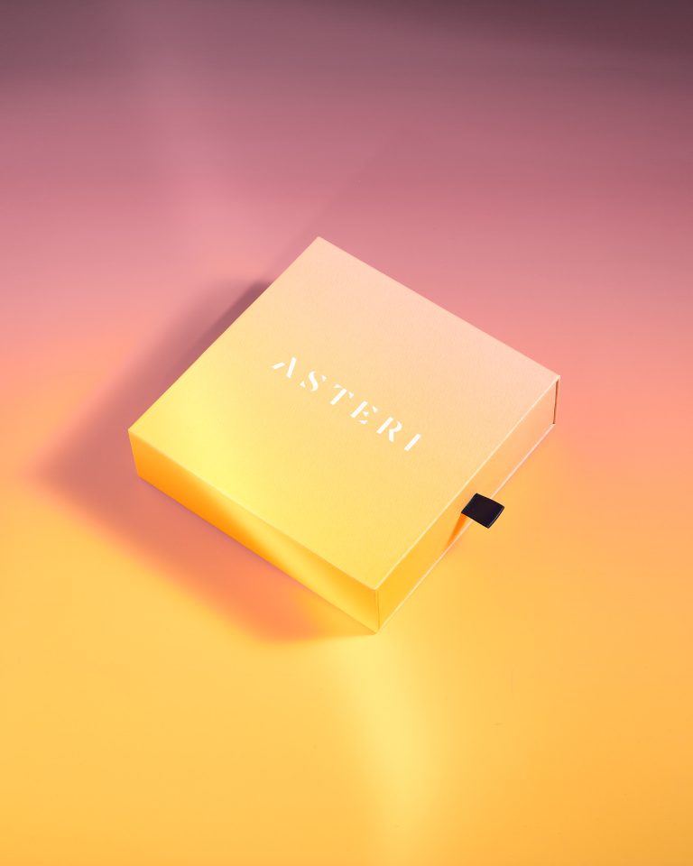 Asteri beauty box on warm pink and yellow gradient backdrop