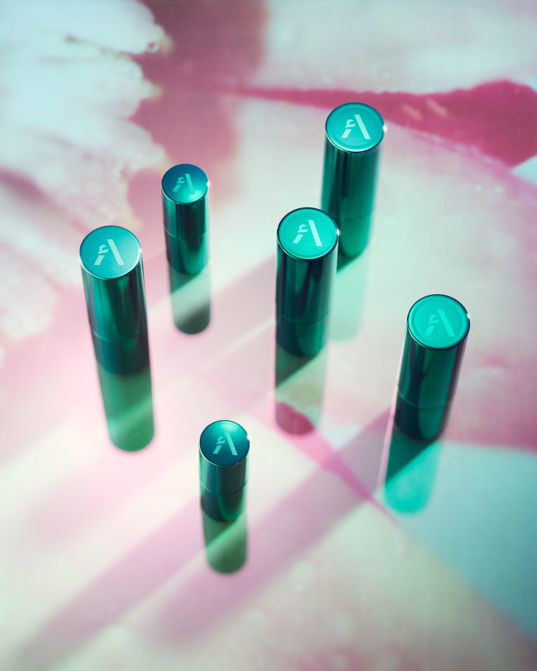Asteri cylindrical beauty products on pink and teal gradient background