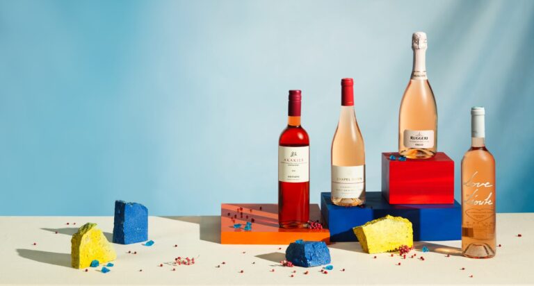 Wine bottles on colourful geometric set with blue backdrop, editorial product photography