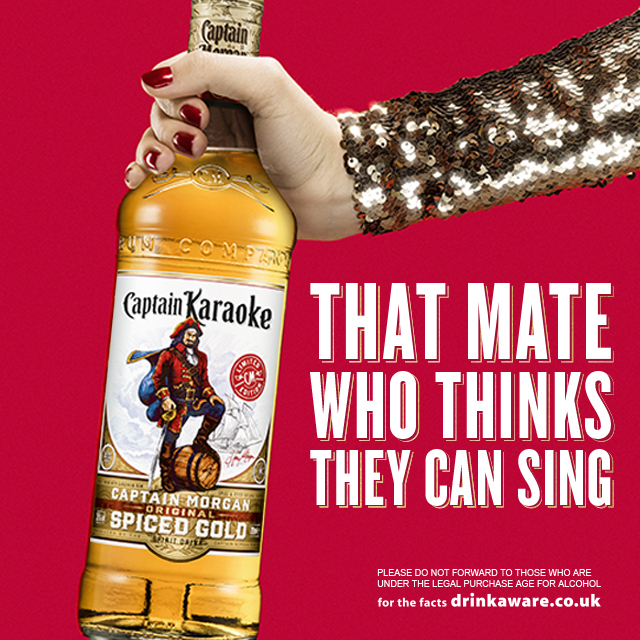 Captain Morgan bottle held in sequin clad arm and hand with campaign typography on red background, advertising image