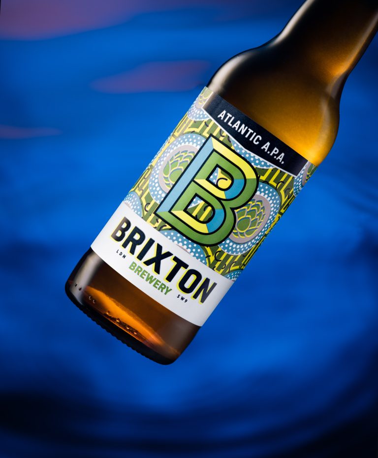 Close-up of Brixton beer bottle with blue water background, studio still life