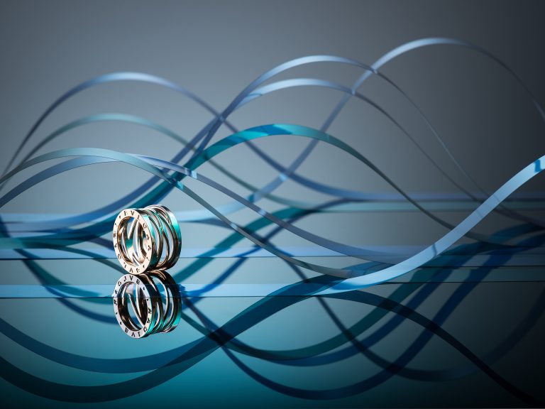 Bulgari ring on reflective surface with flowing blue sculptural backdrop