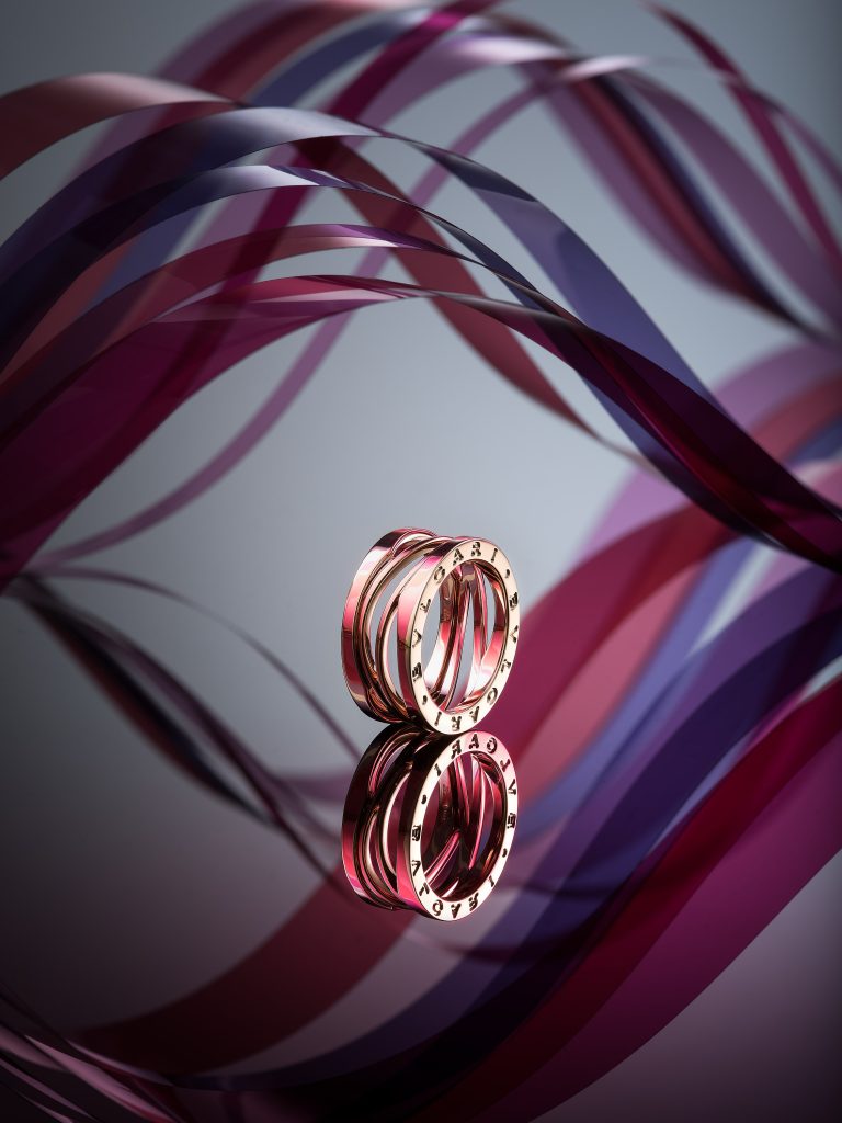 Bulgari ring on reflective surface with flowing red and purple sculptural elements