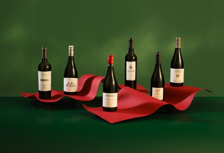 Assorted wine bottles on green background with sculptural red paper set