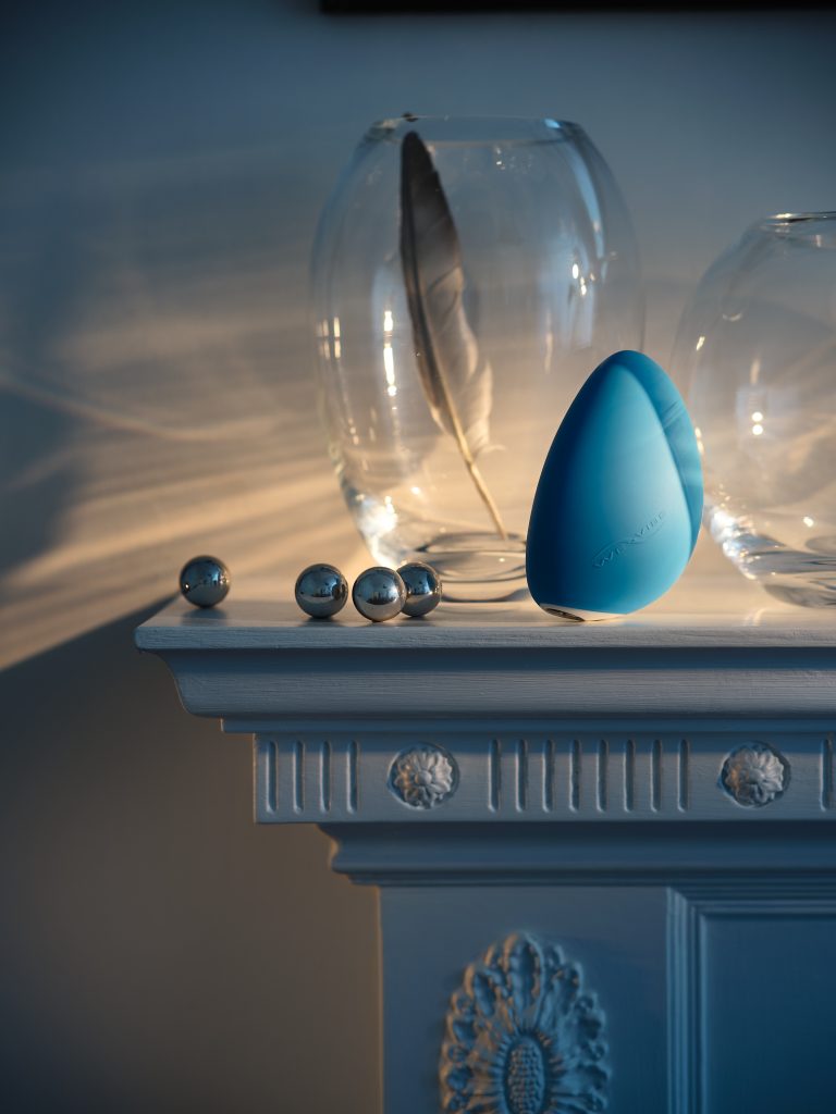 Blue intimate design object with glass dome and metallic spheres on decorative plinth in domestic still life setting