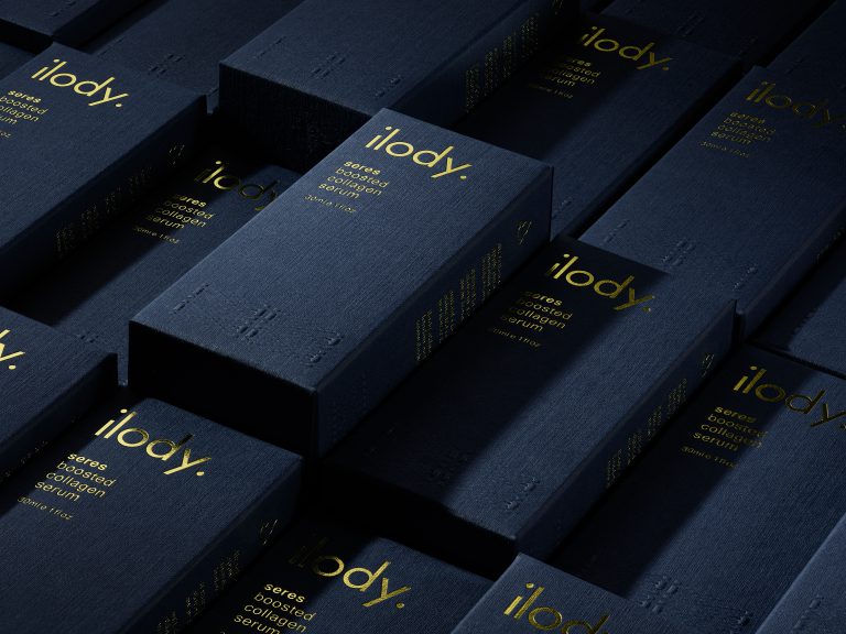 Close-up of Ilody navy skincare packaging with gold foil branding detail