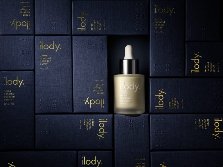 ilody skincare serum bottle surrounded by navy branded boxes in studio still life