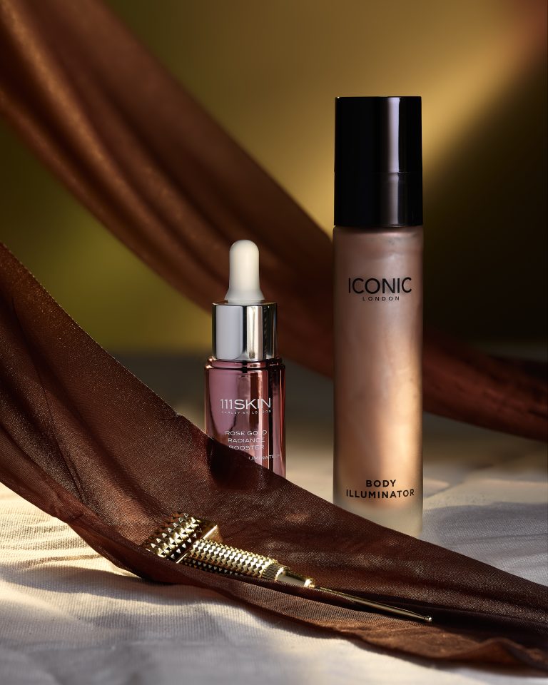 ICONIC London makeup and lip oil products with flowing fabric in beauty still life