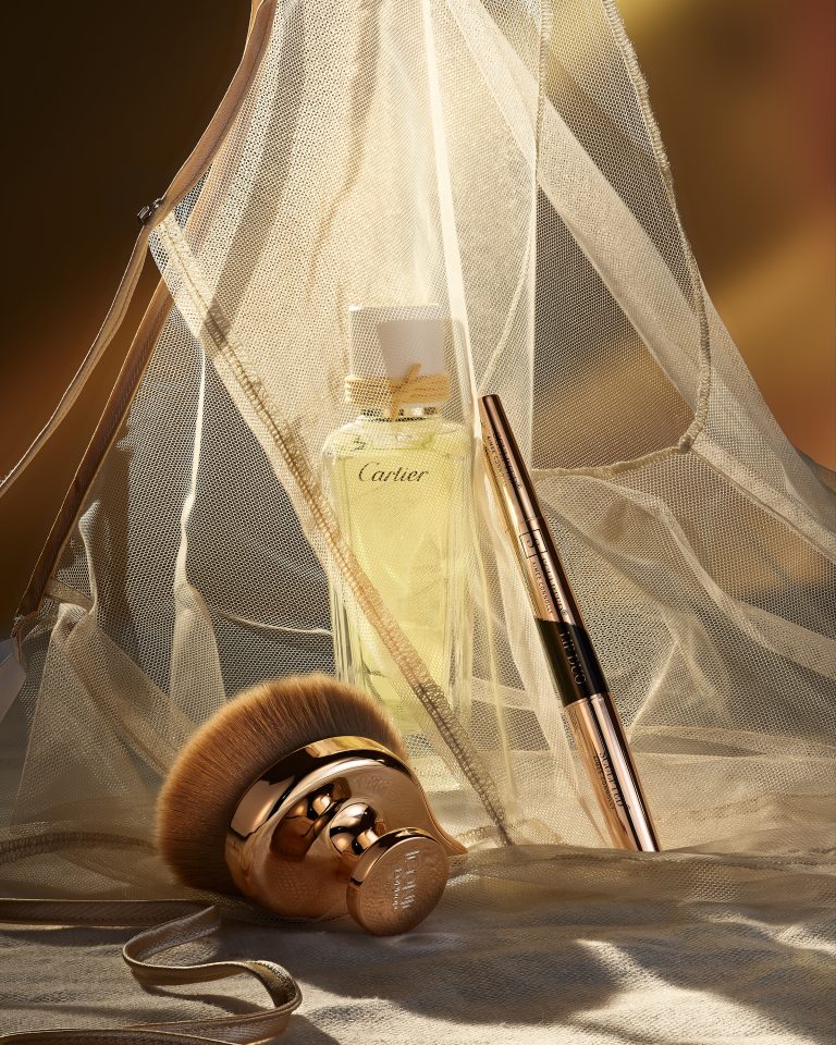 Lancôme perfume bottle with makeup brush and veil fabric in editorial still life