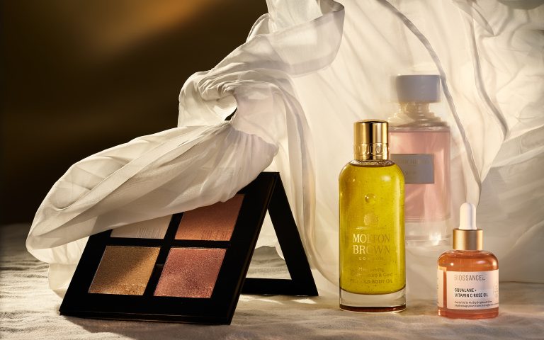 Beauty palette and yellow perfume bottle arranged in warm studio lighting
