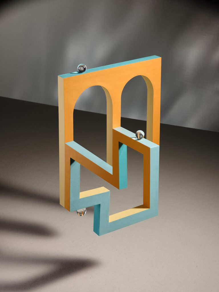 Geometric sculptural structure with orange and blue arches creating optical illusion, studio still life
