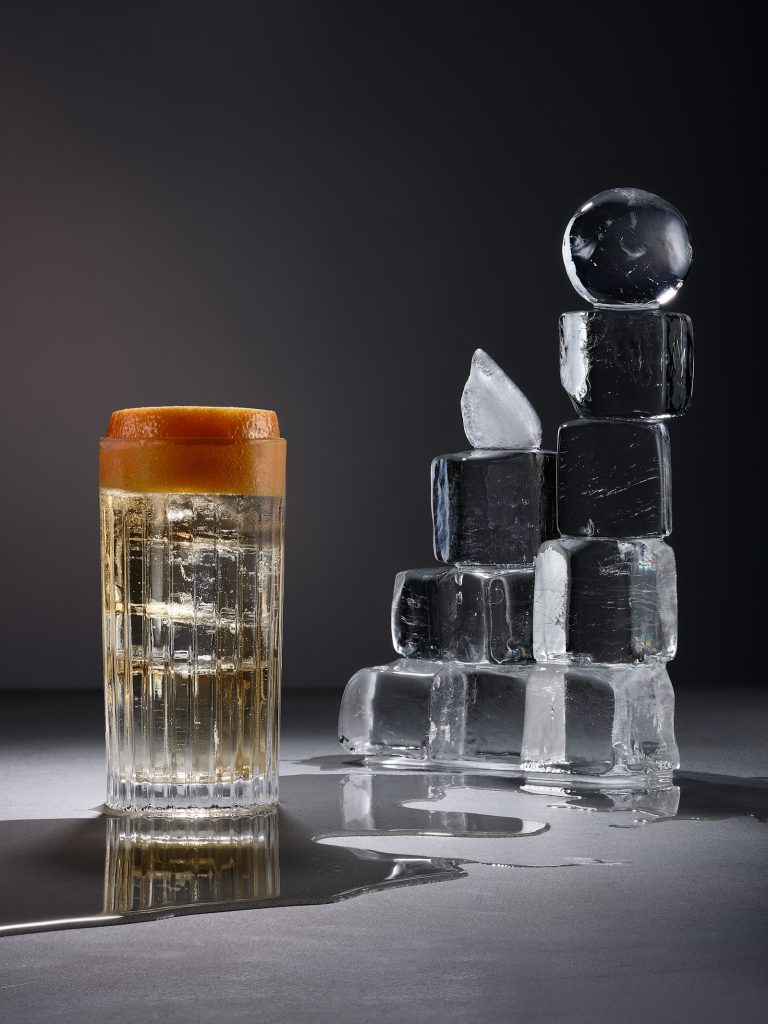Highball drink with stacked ice cubes on dark background, conceptual drinks still life