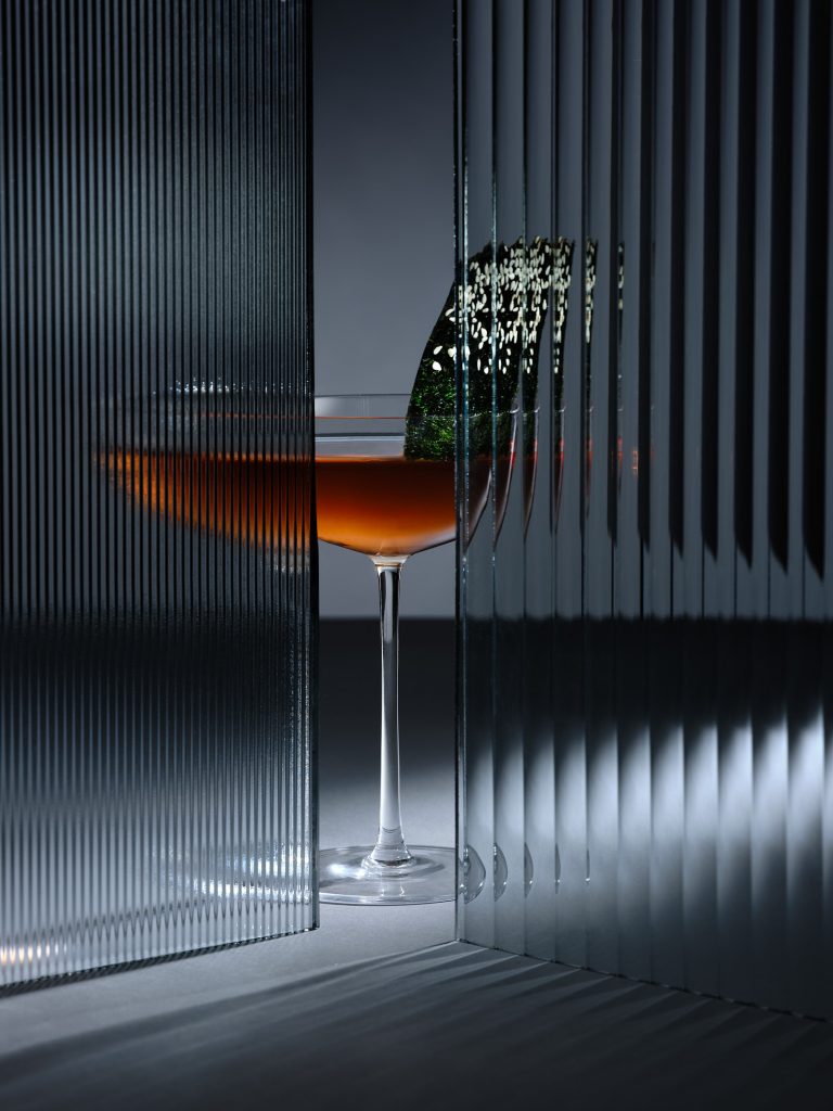Cocktail glass with reflective panels and dramatic lighting, atmospheric composition