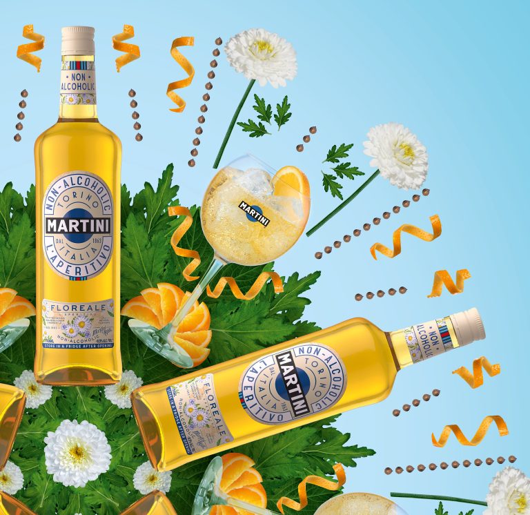 Martini bottle with citrus slices and botanicals on blue background, commercial product photography