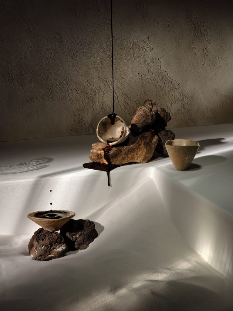 Organic sculptural forms with liquid in white basin, a table top conceptual studio composition