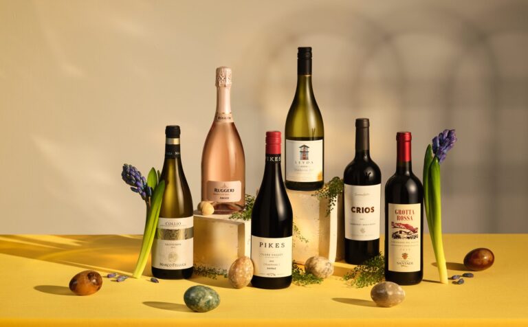 Mixed wine bottles with fruit props on yellow surface, commercial drinks photography