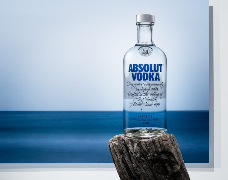 Absolut vodka bottle in front of printed ocean landscape, studio still life