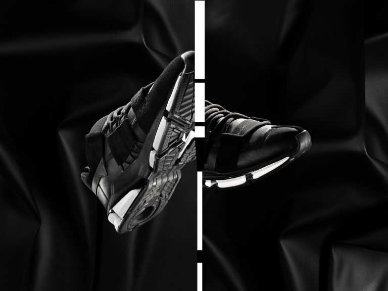 Adidas black trainer in dynamic angled composition with high-contrast lighting