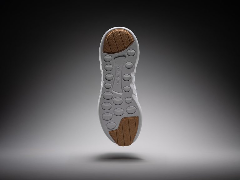 Adidas trainer sole detail suspended against dark background