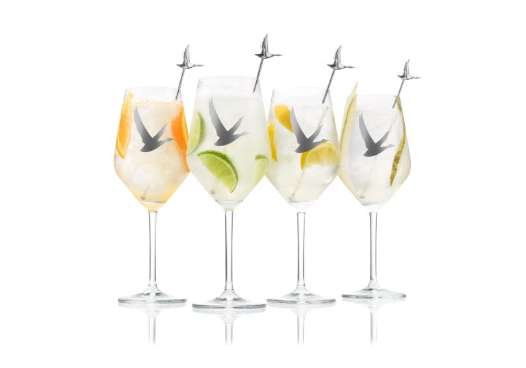 Grey Goose cocktails with citrus garnish and branded stirrers on white background, studio still life