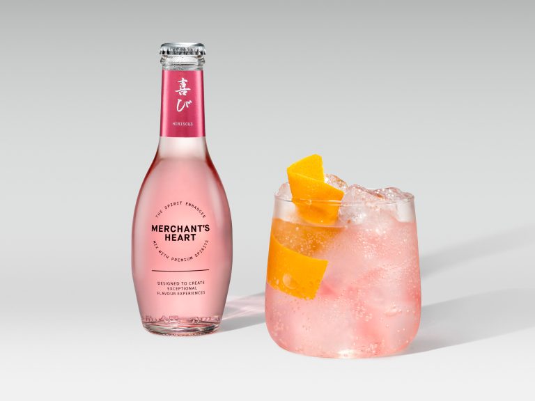 Merchant’s Heart pink mixer bottle with iced cocktail and orange garnish