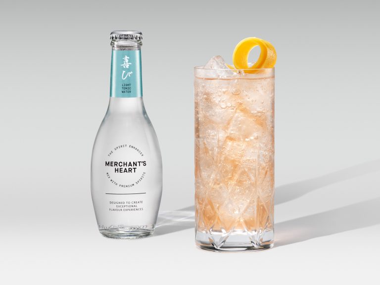 Merchant’s Heart bottle with tall amber drink and orange garnish