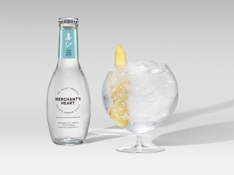 Merchant’s Heart bottle with coupe glass and lemon garnish on white background