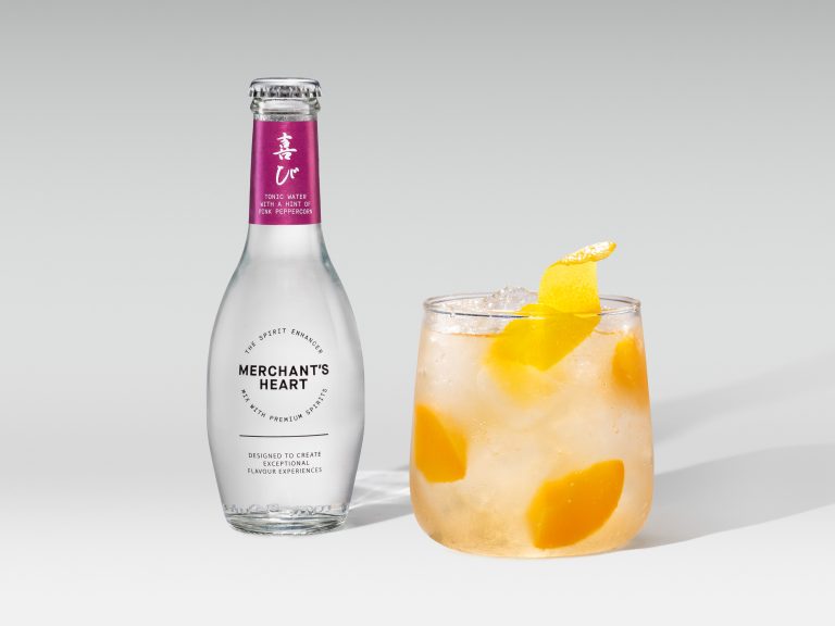 Merchant’s Heart pink mixer bottle with short iced cocktail and orange pieces