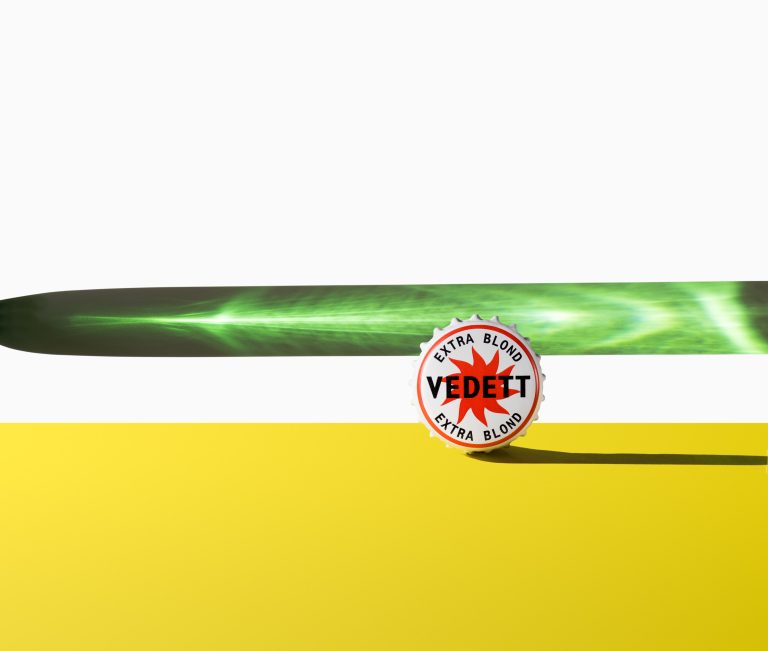 Vedett bottle cap rolling across surface with motion blur, studio composition